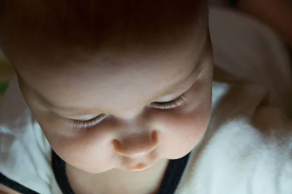 Yüzü alttan aydınlanmış, beyaz bir vücut giysisi içinde, yarı yaşında bir çocuk. Yakın plan.