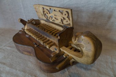 Halk müziği enstrümanı ahşaptan yapılmış hurdy-gurdy el yapımı açık bir klavye kapağı ve gri keten bir tuvalde ejderha kafası şeklinde bir klavye.