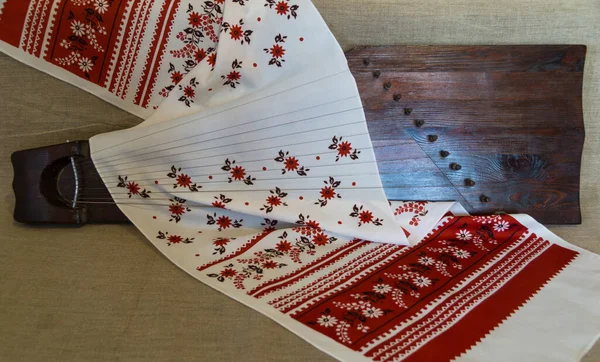 Eski bir Slav halkı, eski bir havlu gibi stilize edilmiş süslü bir bez şerit ile kaplı gri bir arkaplan üzerine Gusli adlı bir müzik aleti dizmişti.