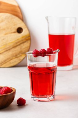 Gri arka plandaki bardakta ahududu içeceği var. Sürahide çilekli limonata. Yan görünüm.