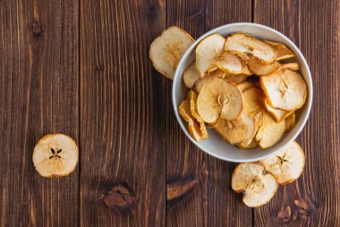 Tahta bir masada, beyaz bir kasede kurutulmuş elma..