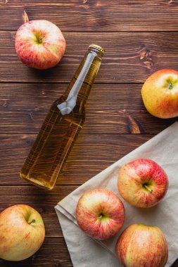 Ahşap bir masada şişede elma şarabı. Taze meyvelerin en üst görüntüsü.