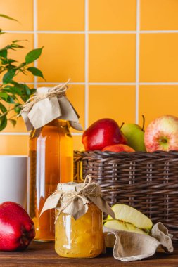 Elma suyu ve reçel, kahverengi bir sepetle ahşap bir masada. Taze meyvelerin yan görünümü.