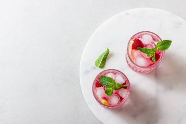 Soğuk ahududu içecekleri, mermerde buzlu ve hafif arka planda. Nane ve limonlu ferahlatıcı bir dut kokteyli..