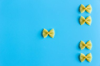 Mavi arka planda fotokopi alanı olan çiğ makarna. İtalyan mutfak malzemelerinin üst görünümü.
