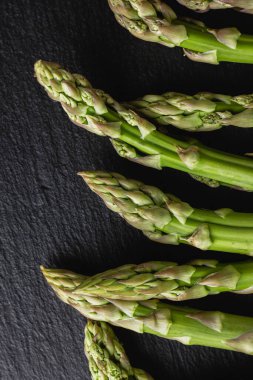 Siyah arka planda yeşil kuşkonmaz. Taze ve doğal pişmemiş kuşkonmaz. Yakın çekim. Sağlıklı bitkiler..