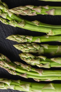 Siyah arka planda yeşil kuşkonmaz. Taze ve doğal pişmemiş kuşkonmaz. Yakın çekim. Sağlıklı bitkiler..