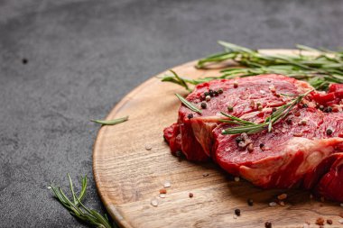 Tahta tepside çiğ et. Büyük bir parça pişmemiş kırmızı et ve koyu arkaplanda biberiye..