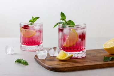 Ahşap kesme tahtasındaki buzlu ahududu kokteyli. Nane ve limonlu ferahlatıcı bir meyve suyu..