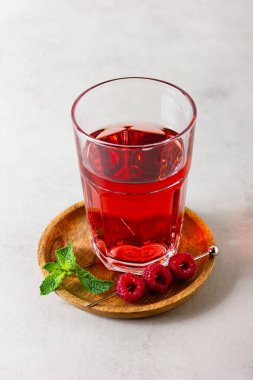 Arka plandaki bardakta ahududu içeceği var. Tahta tabakta çilekli limonata. Yan görünüm.