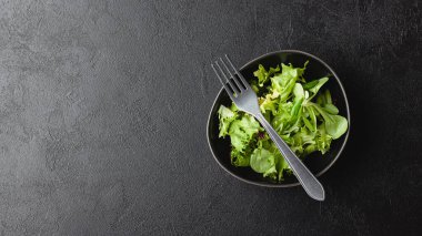 Siyah masada yeşil salata yaprakları. Fotokopi alanı olan taze ve sağlıklı yiyecekler. Üst görünüm.