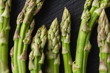 Siyah arka planda yeşil kuşkonmaz. Taze ve doğal pişmemiş kuşkonmaz. Yakın çekim. Sağlıklı bitkiler..