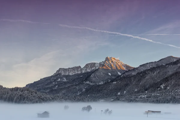 Ciel coloré au lever du soleil avec énorme montagne et prairie brumeuse — Photo