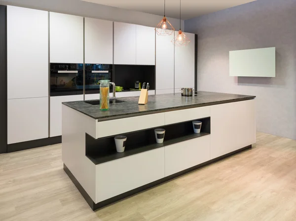 Современная плоская белая кухня с островом приготовления пищи и телевизором — стоковое фото