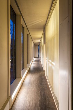 Endüstriyel parkeden bir ahşap ofis koridoru. Geceleri pencere önü ve aydınlatma.