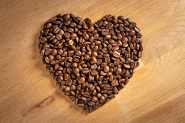 Kahverengi kavrulmuş kahve çekirdekleri meşe ağacından arka planda aşk kalbi şeklinde.