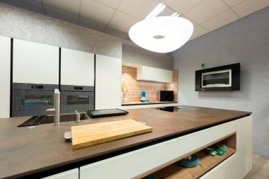 Modern mutfakta ahşap oyuğu ve tasarımcısı serbest lamba olan büyük bir ahşap taş ada manzarası var.