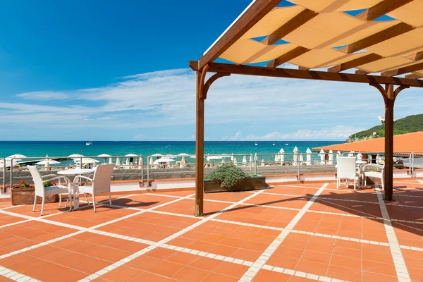 Pomarańczowy płytkami tarasie z biurka i krzesła z cień dach na błękitne morze — Zdjęcie stockowe