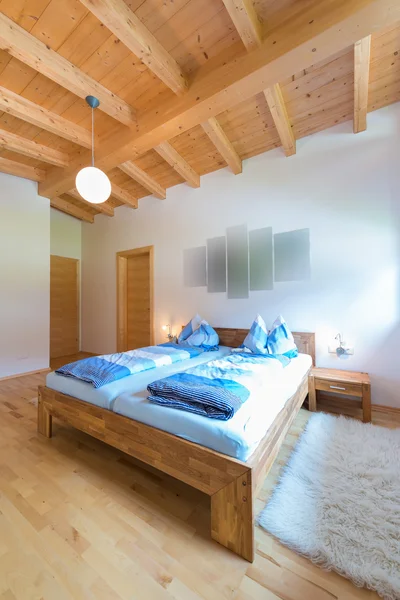 Vertical shot of wooden bed in bedroom at timber house — Stock Photo, Image