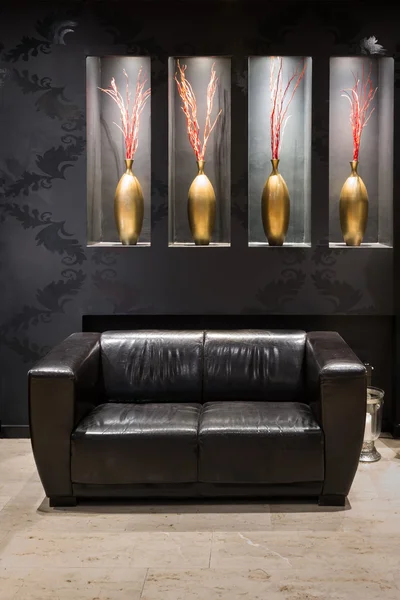 Чорний шкіряний диван в антеромі з золотою квітковою вазою — стокове фото