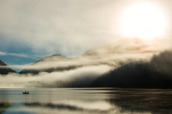 Mystic dust over austrian alps lake with fisher boat and fog — Stock Photo, Image