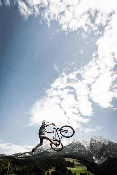 Mladá trik senzace biker skoky trik vysoké hory alp — Stock fotografie