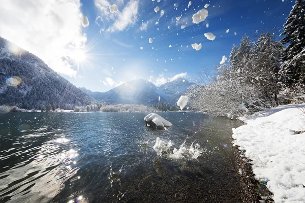 Ice and snow pieces flying into lake in sunny weather winter landscape — Stock Photo, Image