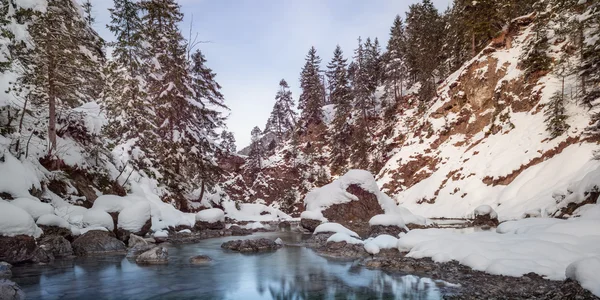 Маленькая река между камнями и снежными скалами зимой — стоковое фото