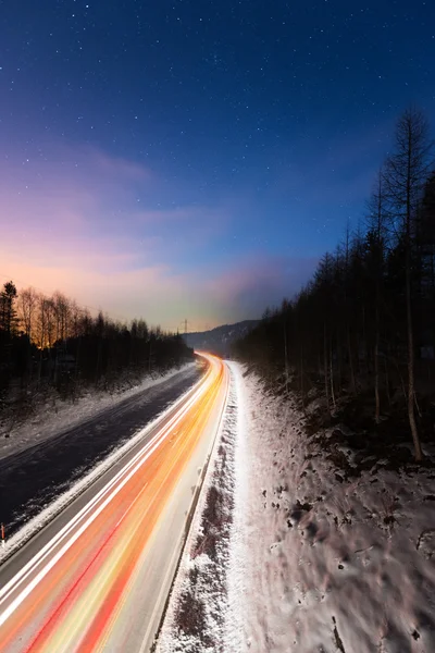 Světla auta na ulici v zimní noci s barevné nebe — Stock fotografie