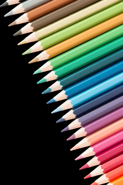 Beaucoup de crayons de couleur dans une rangée sur fond noir — Photo