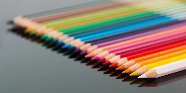 Arranged colored wood pencils lying on black background — Stock Photo, Image