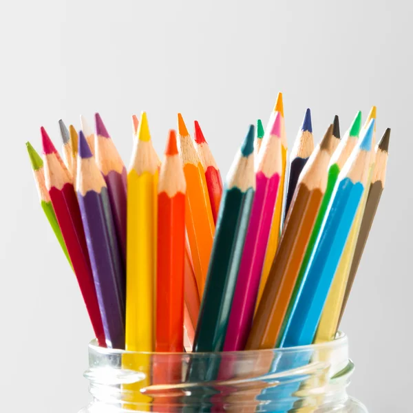 Nombreux crayons en bois de couleur debout en verre sur blanc — Photo