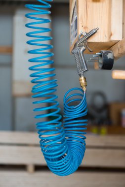 Blue compressed pneumatic air hose with pistol hanging at screw clipart