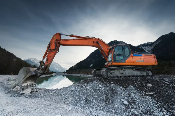 Gran excavadora de pala de pie sobre piedras de grava antes del lago — Foto de Stock