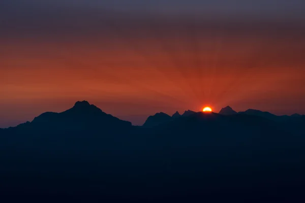 Sunset at mountain alps in austria with red sky and sun beams — Stock Photo, Image