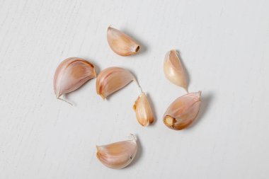 Soyulmuş sarımsak karanfilleri beyaz bir masada..