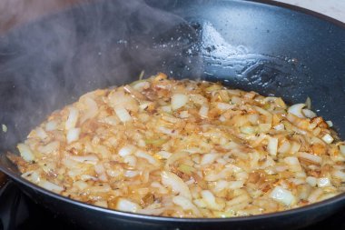 Tereyağında tavada kızartılmış soğan. Buhar tavadan çıkıyor..