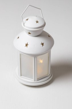 Yıldız takan beyaz Noel feneri. Fener parlar ve beyaz bir masanın üzerinde durur..