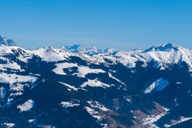 Zell am See 'deki Schmitten kayak alanındaki karlı dağların manzarası. Arka planda bulutlu güzel bir gökyüzü var..