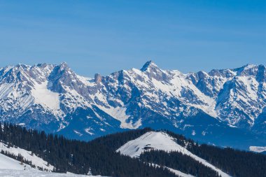 Zell am See 'deki Schmitten kayak alanındaki karlı dağların manzarası. Arka planda bulutlu güzel bir gökyüzü var..