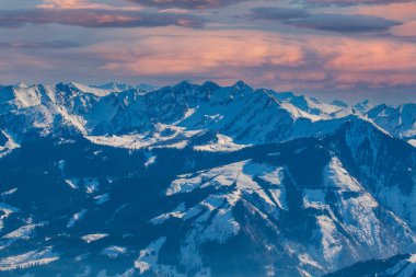 Zell am See 'deki Schmitten kayak alanındaki karlı dağların manzarası. Arka planda bulutlu güzel bir gökyüzü var..