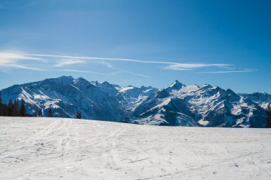 Zell am See 'deki Schmitten kayak alanındaki karlı dağların manzarası. Arka planda bulutlu güzel bir gökyüzü var..