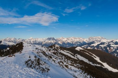 Zell am See 'deki Schmitten kayak alanındaki karlı dağların manzarası. Arka planda bulutlu güzel bir gökyüzü var..