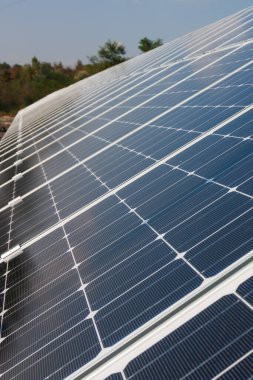 Fotovoltaik enerji santrali panelleri güneşten enerji elde etmek için. Arka planda beyaz bulutlu güneşli mavi bir gökyüzü.