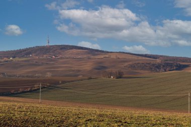 Avrupa 'daki Çek Cumhuriyeti' nin Strazovice yakınlarındaki St. Barbora 'nın dalgalı manzarası ve şapeli. Arka planda beyaz bulutlu mavi bir gökyüzü var..