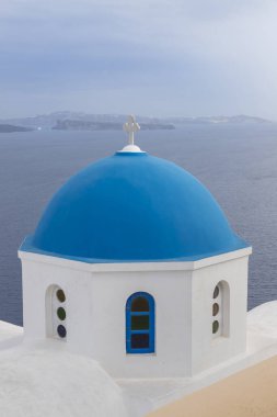 Güneşli havalarda Oia şehrinin manzarası. Arka plan beyaz bulutlu mavi bir gökyüzü. Yunanistan 'ın Santorini adasında şehir.