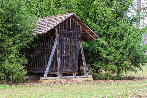 Big wooden feeder in the forest. There are coniferous trees around.