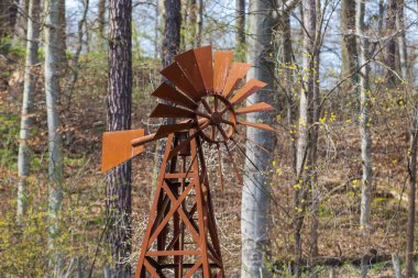 Old metal rusty pinwheel near the forest. clipart