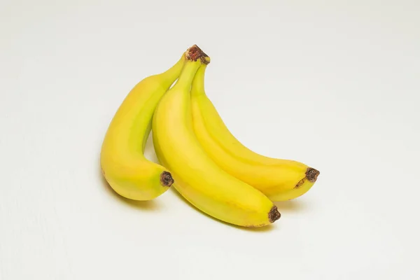 Três Bananas Amarelas Suas Peles Jazem Uma Mesa Branca — Fotografia de Stock