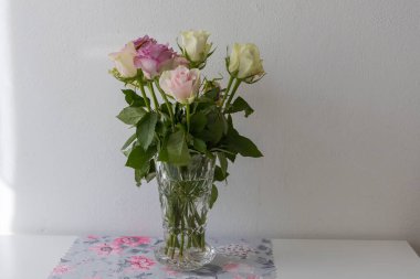 Pastel colored roses in a vase on a tabl